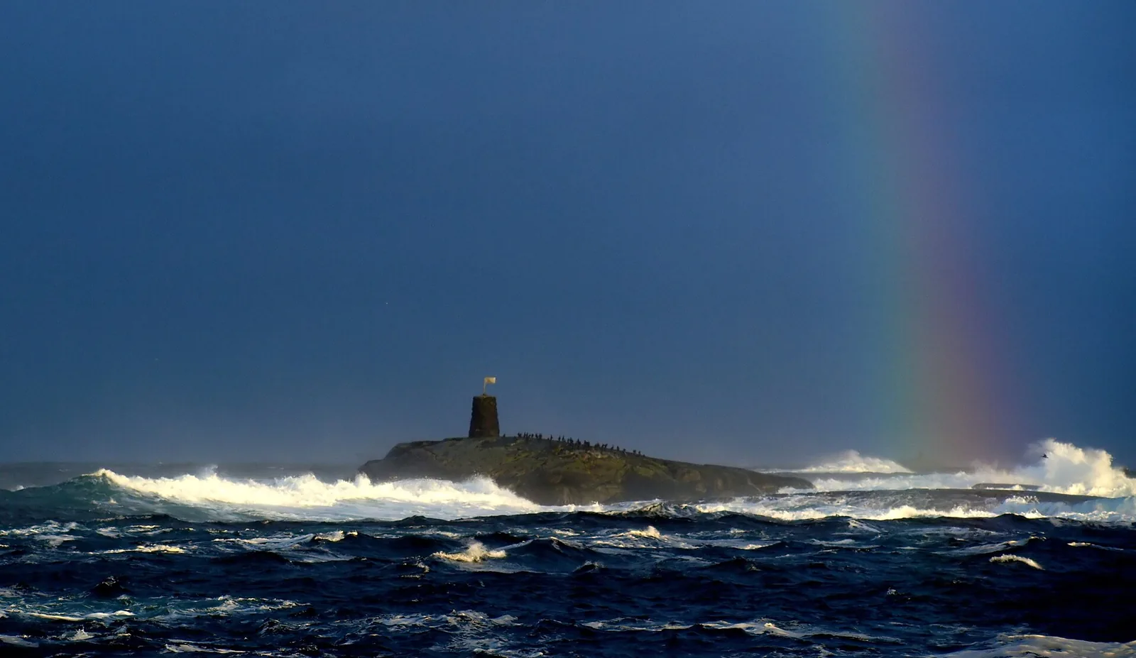 Rough dark blue seas breaking around a rocky skerry off Hustadvika